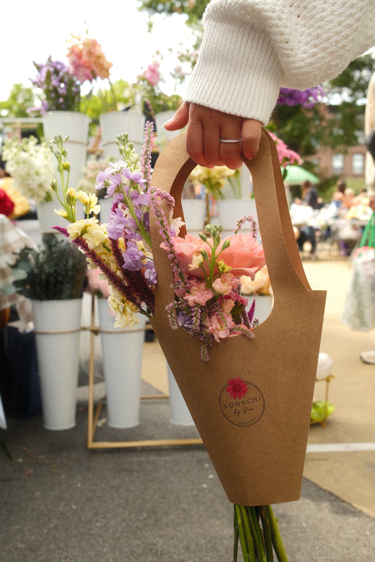 A person holding a lush floral arrangement by noonchi by bex